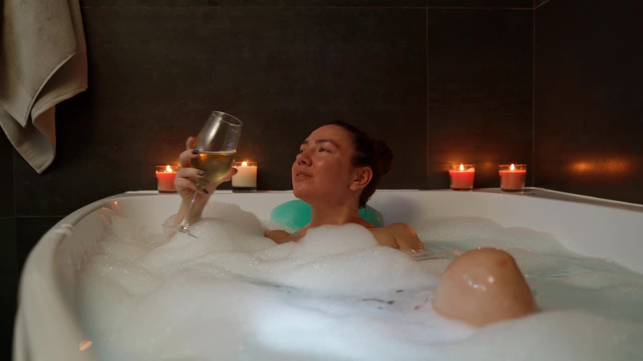 女人喝着酒在浴缸里放松视频素材