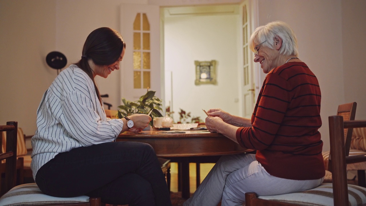 快乐的女看护者和老女人在家打牌视频素材