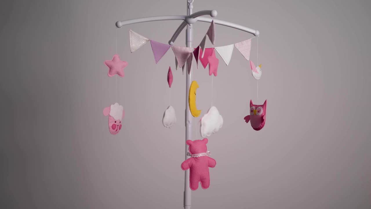 婴儿移动与粉红色的手缝动物和鸟玩具与黄色的月亮在白色的墙壁背景。视频下载