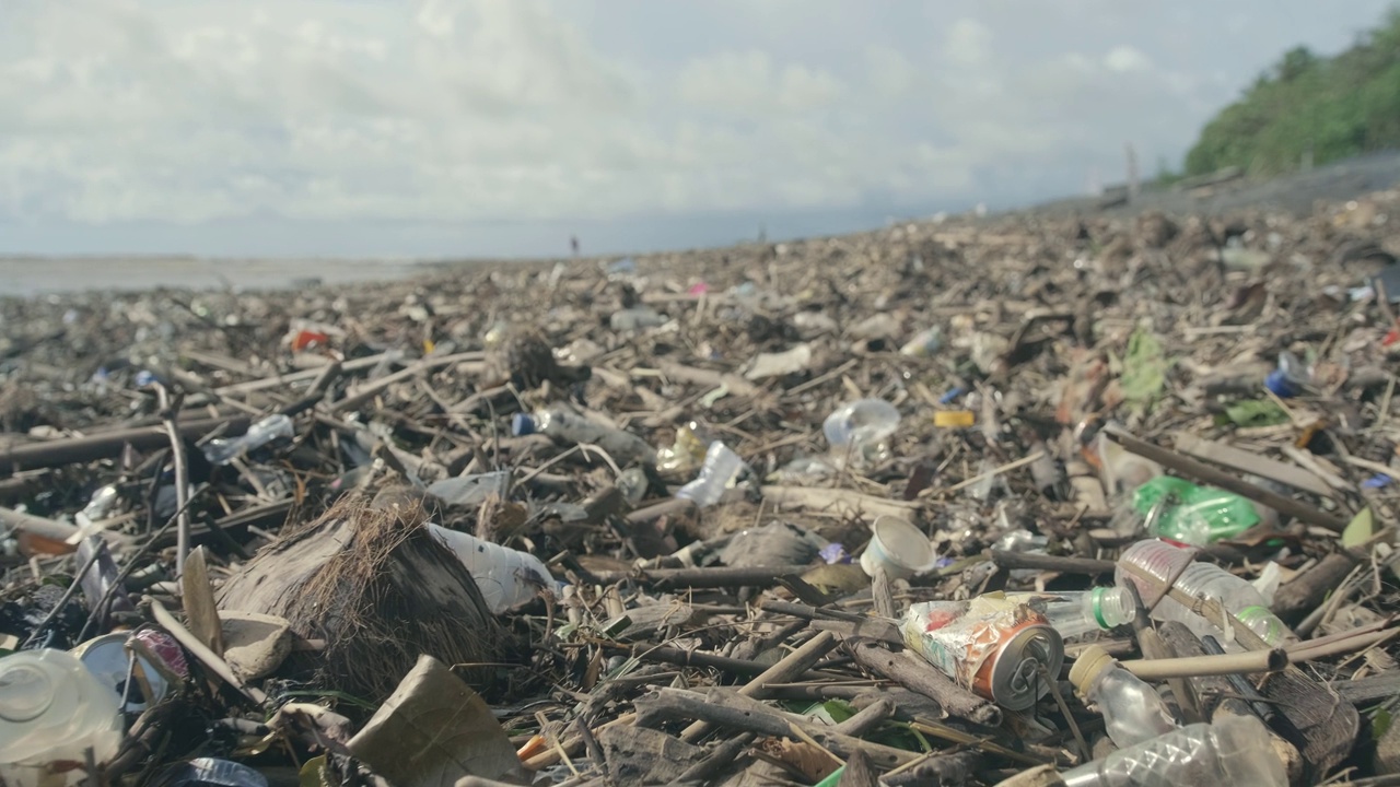 塑料瓶、塑料袋和其他垃圾倾倒在海洋海滩的黑色沙滩上视频素材