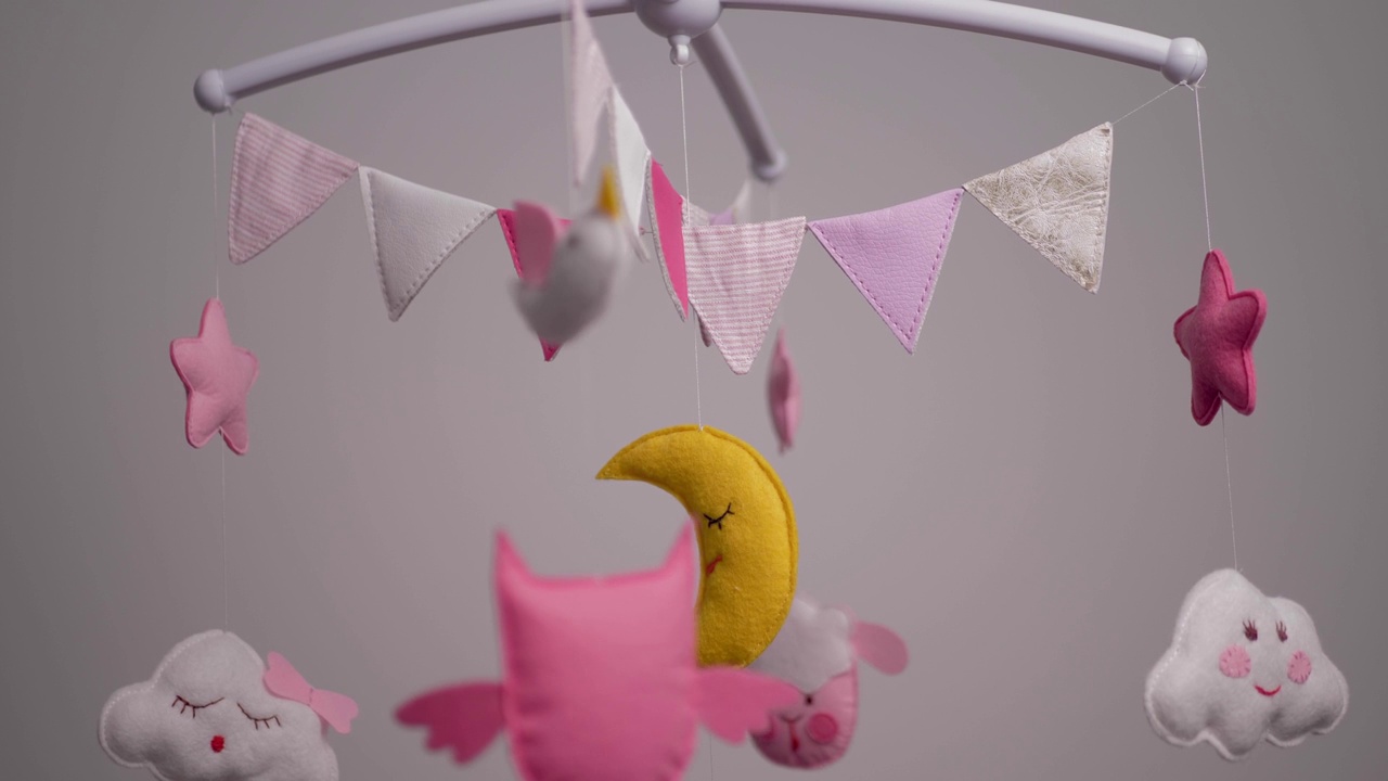 婴儿移动与粉红色的手缝动物和鸟玩具与黄色的月亮在白色的墙壁背景。视频下载