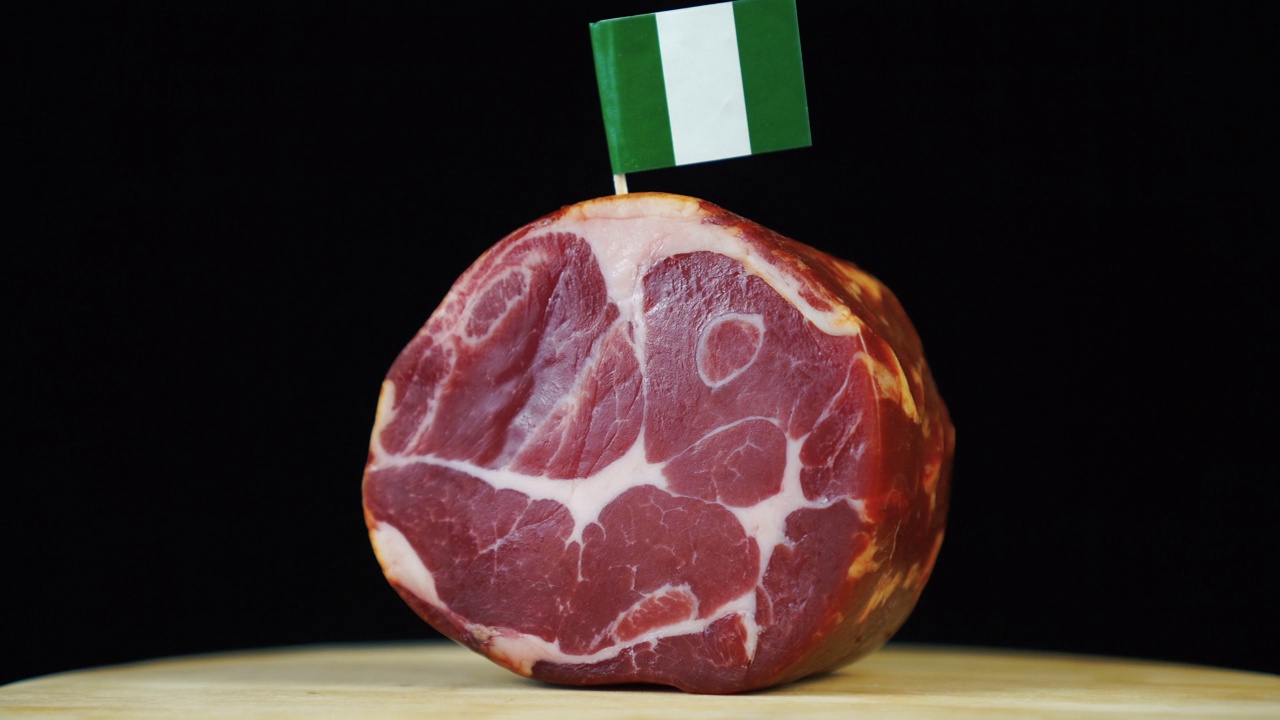 美味的烟熏里脊配尼日利亚小旗，黑色背景上的一块肉旋转着。视频下载
