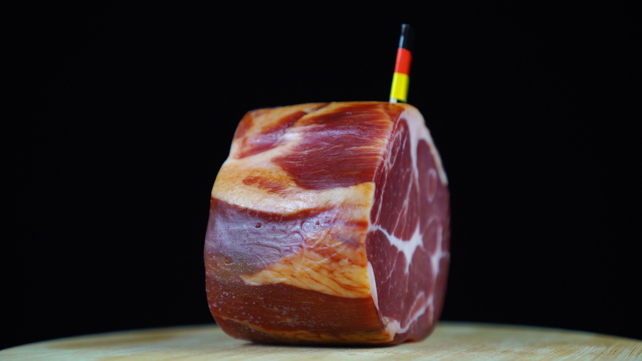 美味的烟熏里脊肉配德国小旗，黑色背景上的一块肉旋转着。视频下载