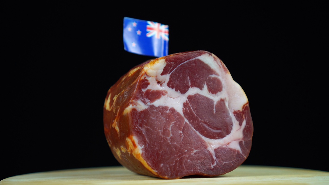 美味的熏里脊肉配新西兰小旗，黑色背景上旋转的肉片。视频素材