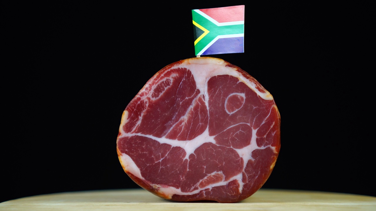 美味的烟熏里脊配南非小旗，黑色背景上的一块肉旋转着。视频素材
