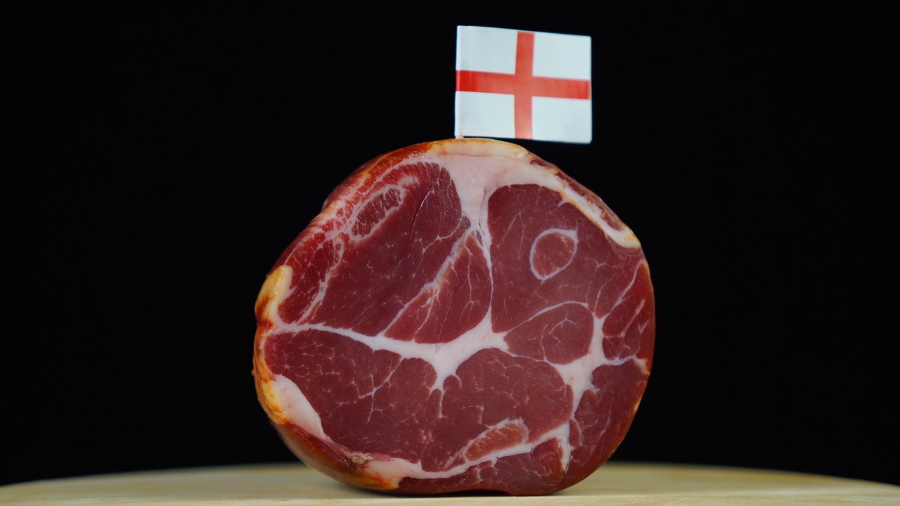 美味的烟熏里脊肉配英格兰小旗，黑色背景上的一块肉旋转着。视频下载