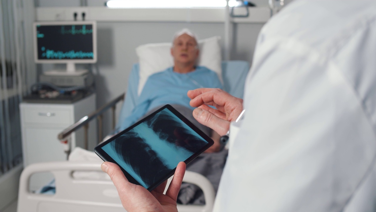 护士照顾躺在床上的老年病人，医生检查肺部x光片视频素材