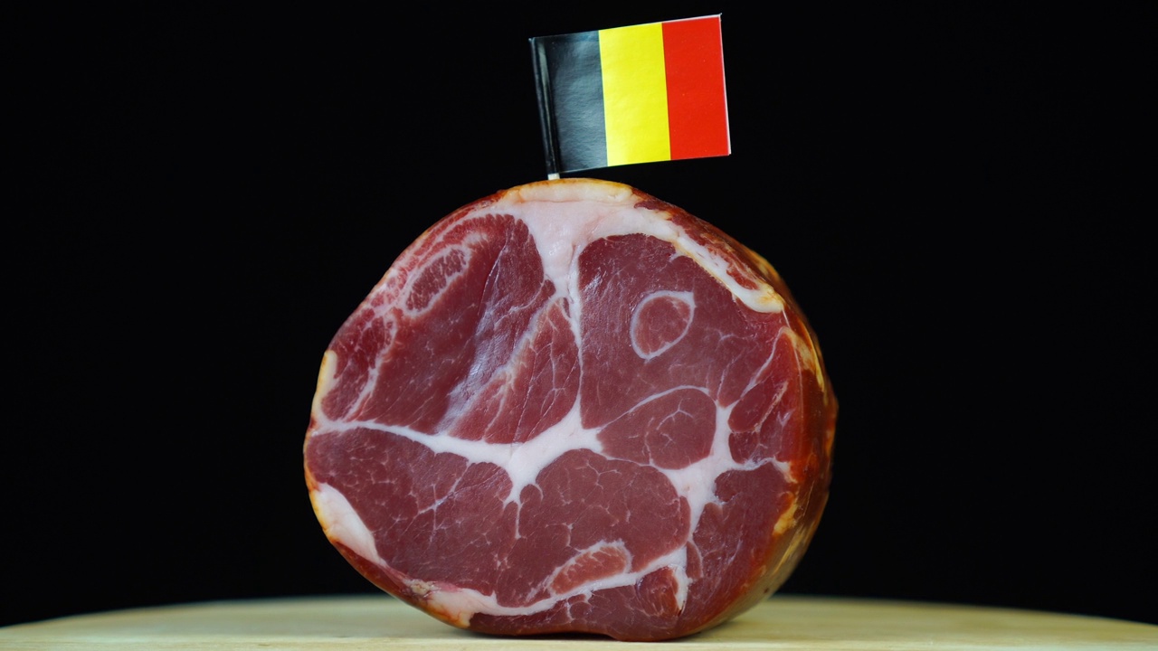 美味的烟熏里脊肉配比利时小旗，黑色背景上的一块肉旋转着。视频下载