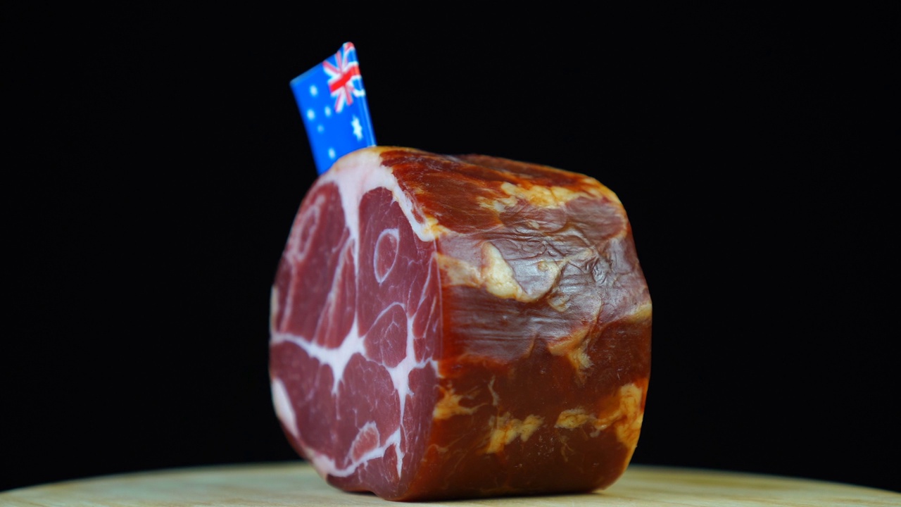 美味的烟熏里脊肉配上澳大利亚国旗，黑色背景上的一块肉旋转着。视频下载