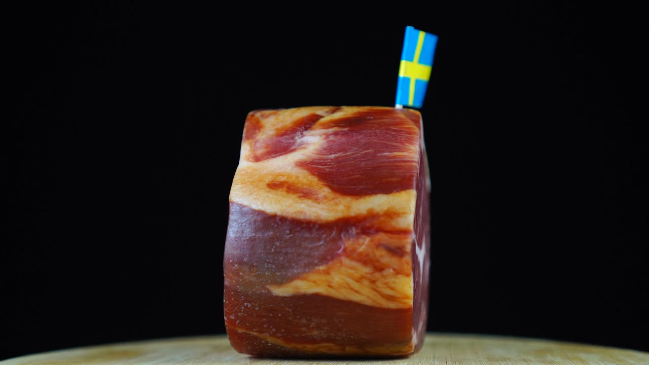美味的烟熏里脊肉配瑞典小旗，黑色背景上的一块肉旋转着。视频下载