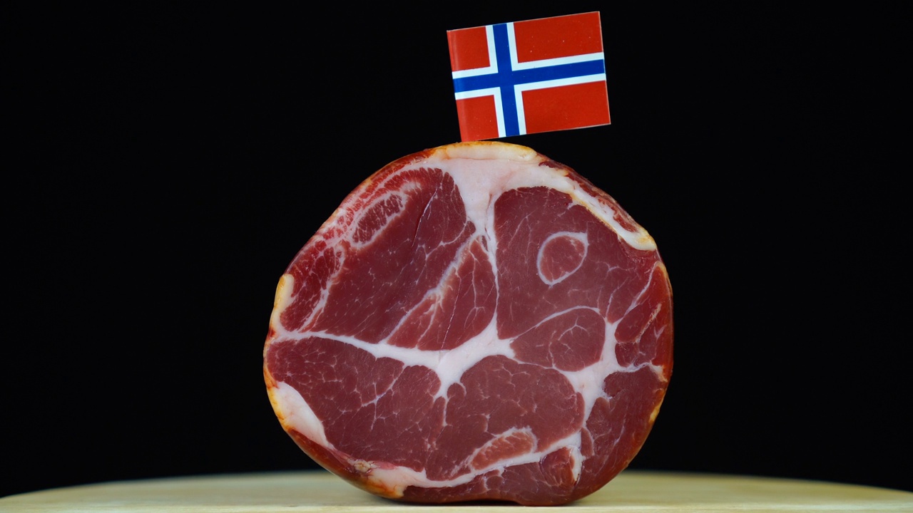 美味的烟熏里脊肉配挪威小旗，黑色背景上的一块肉旋转着。视频素材