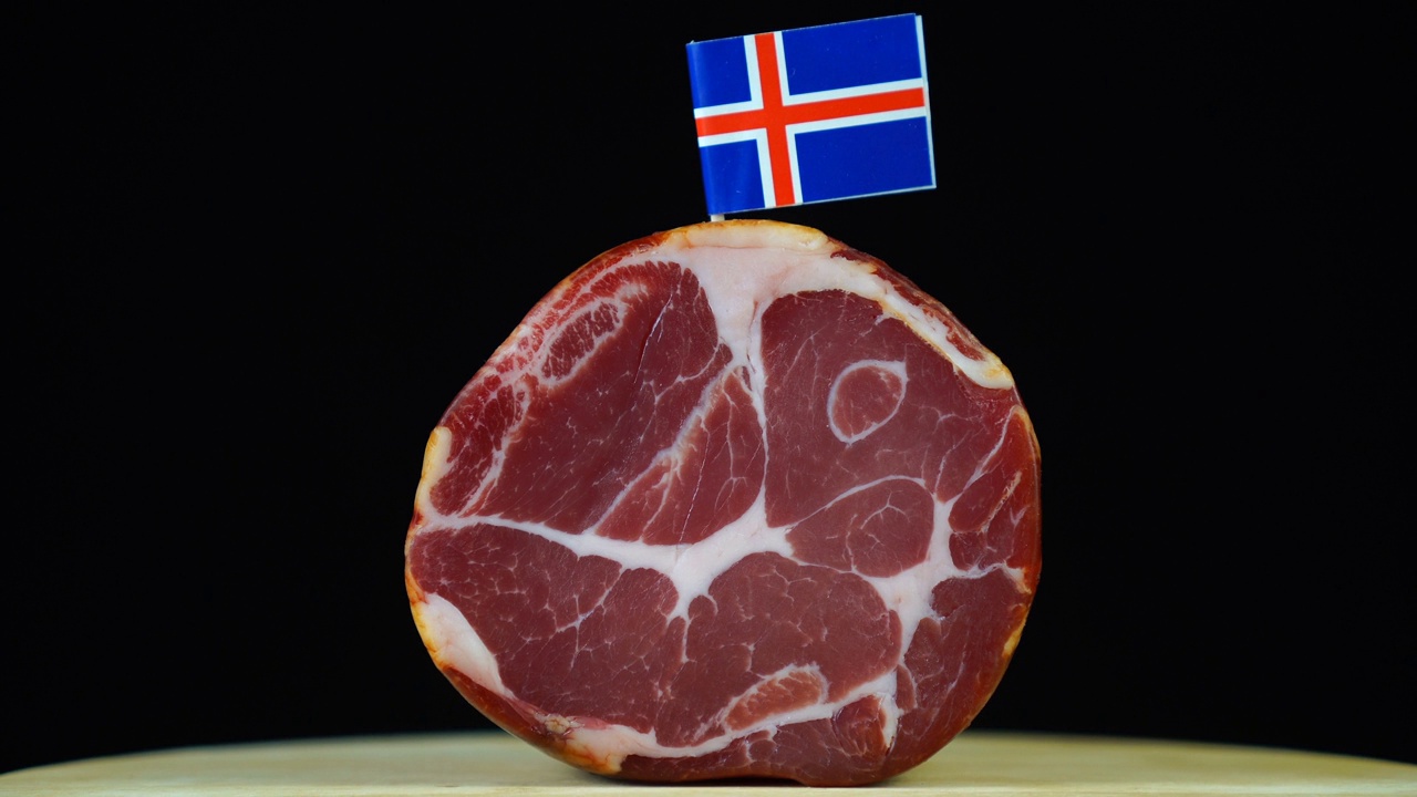 美味的烟熏里脊配冰岛小旗，黑色背景上的一块肉旋转着。视频下载