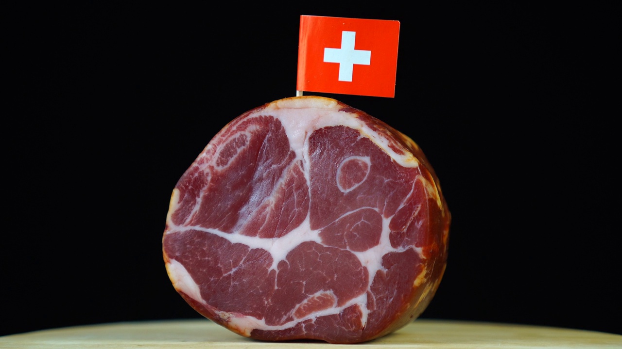 美味的烟熏里脊配上瑞士小旗，黑色背景上的一块肉旋转着。视频下载