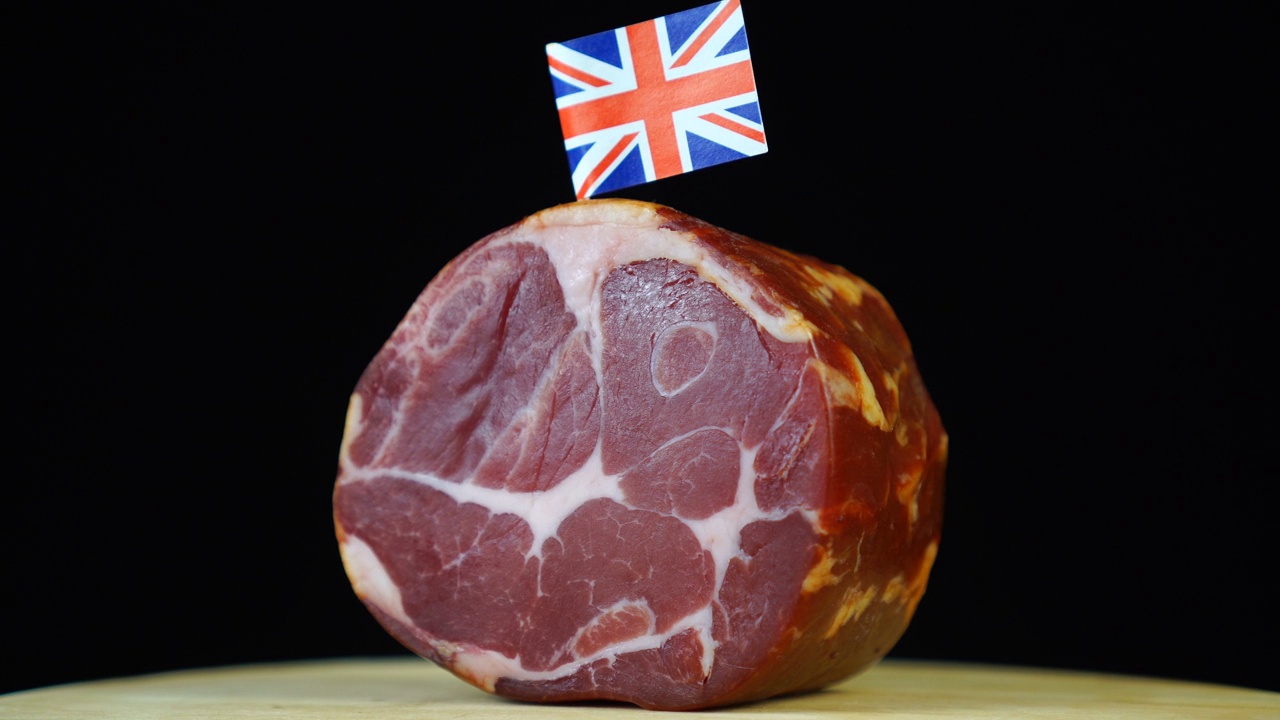 美味的熏里脊肉配上英国的小旗，黑色背景上的一块肉旋转着。视频下载