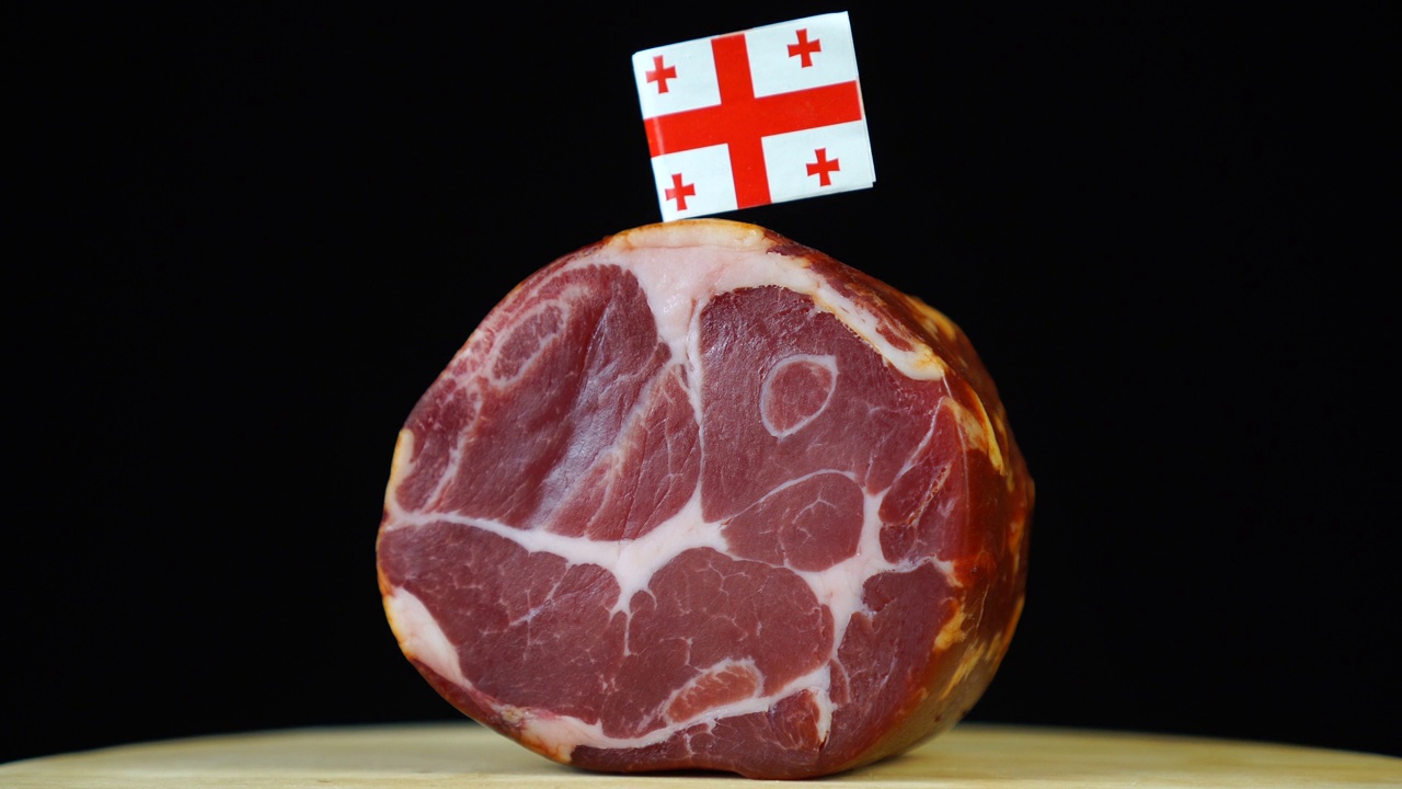 美味的烟熏里脊肉配佐治亚小旗，黑色背景上的一块肉旋转着。视频下载
