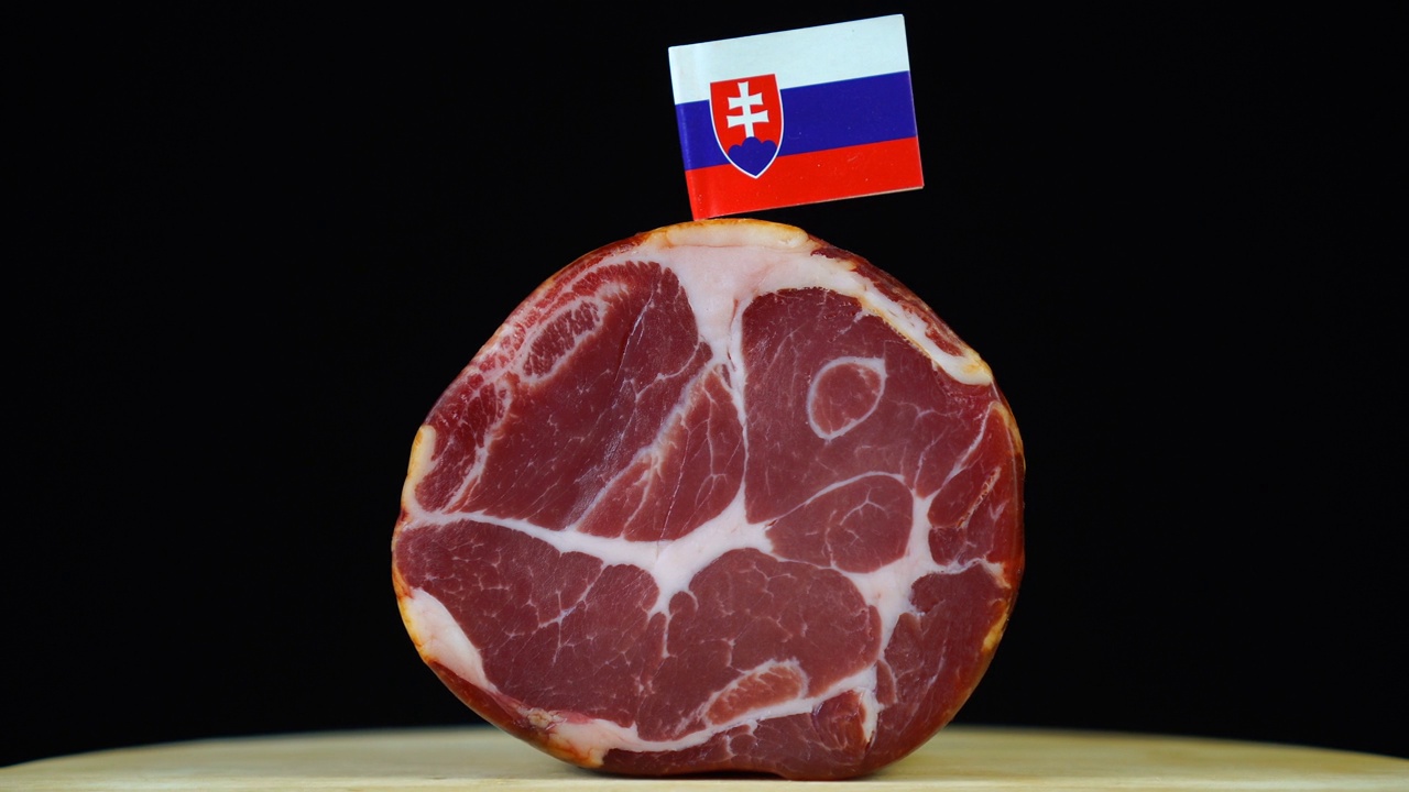 美味的烟熏里脊肉配斯洛伐克小旗，黑色背景上的一块肉旋转着。视频下载