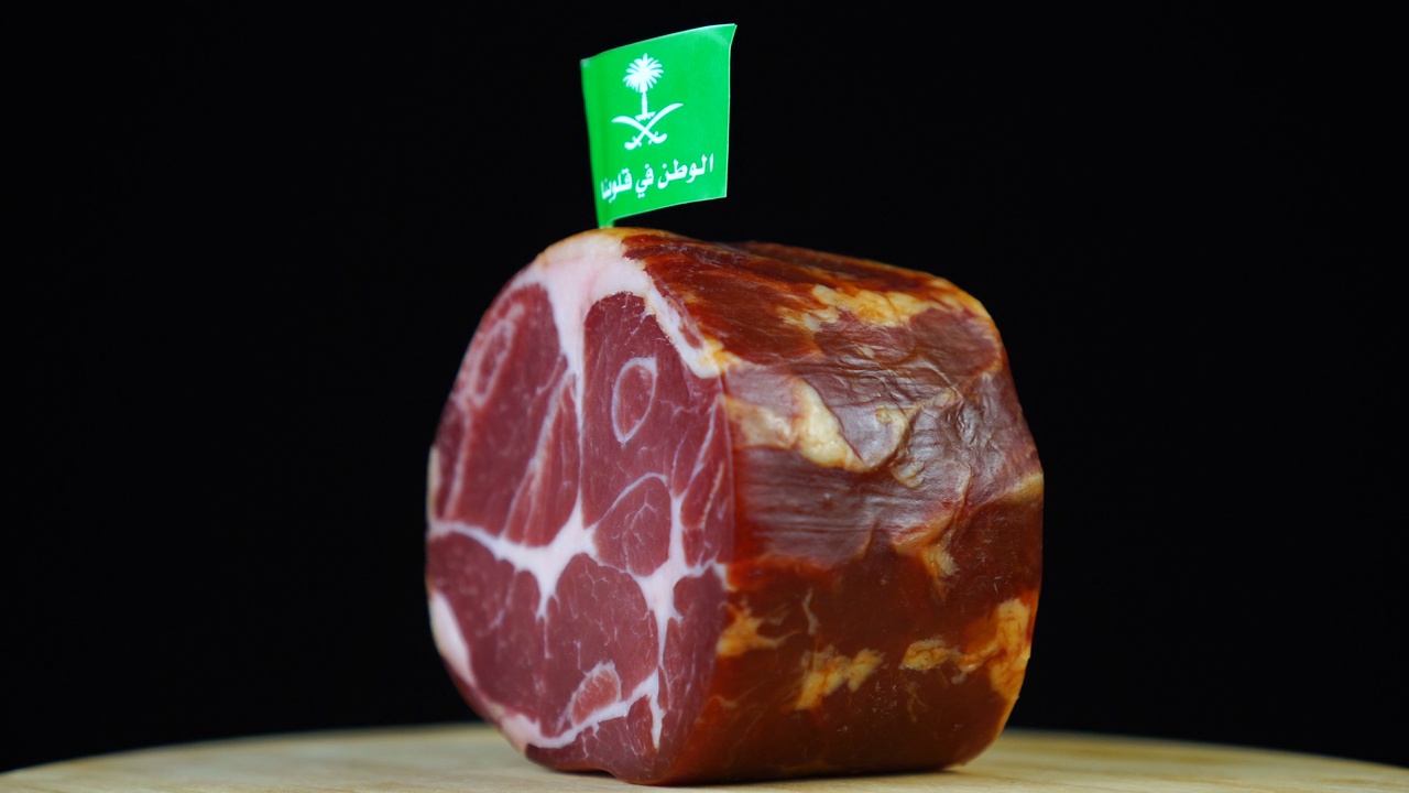 美味的烟熏里脊肉配沙特阿拉伯的小旗，黑色背景上的一块旋转的肉。视频下载
