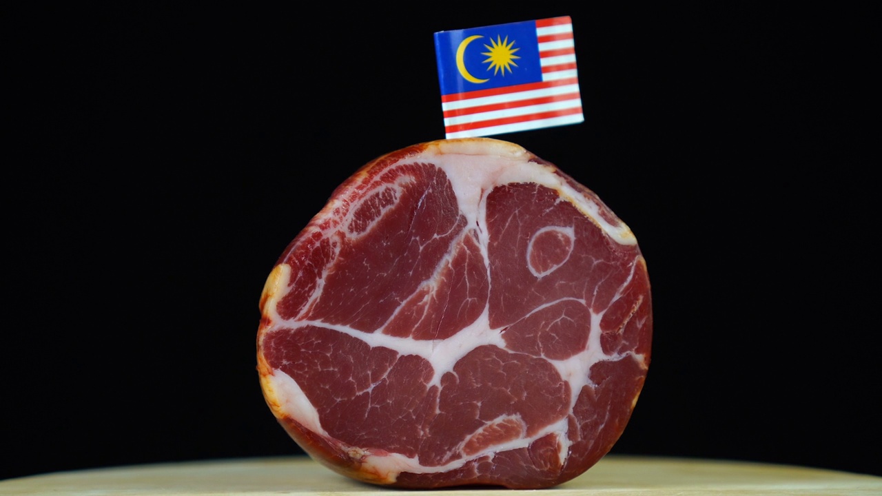 美味的熏里脊肉配上马来西亚国旗，黑色背景上的一块肉旋转着。视频下载