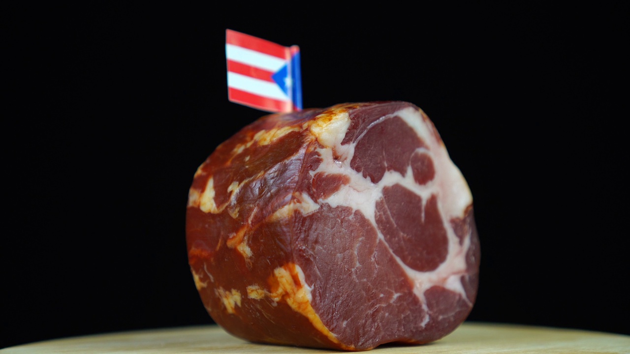 美味的熏里脊肉配波多黎各小旗，黑色背景上的一块肉旋转着。视频下载