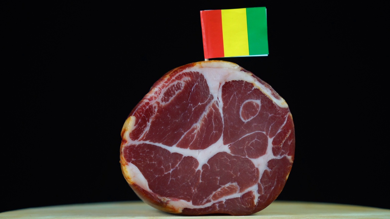 美味的熏制里脊配几内亚小旗，黑色背景上旋转的肉片。视频下载