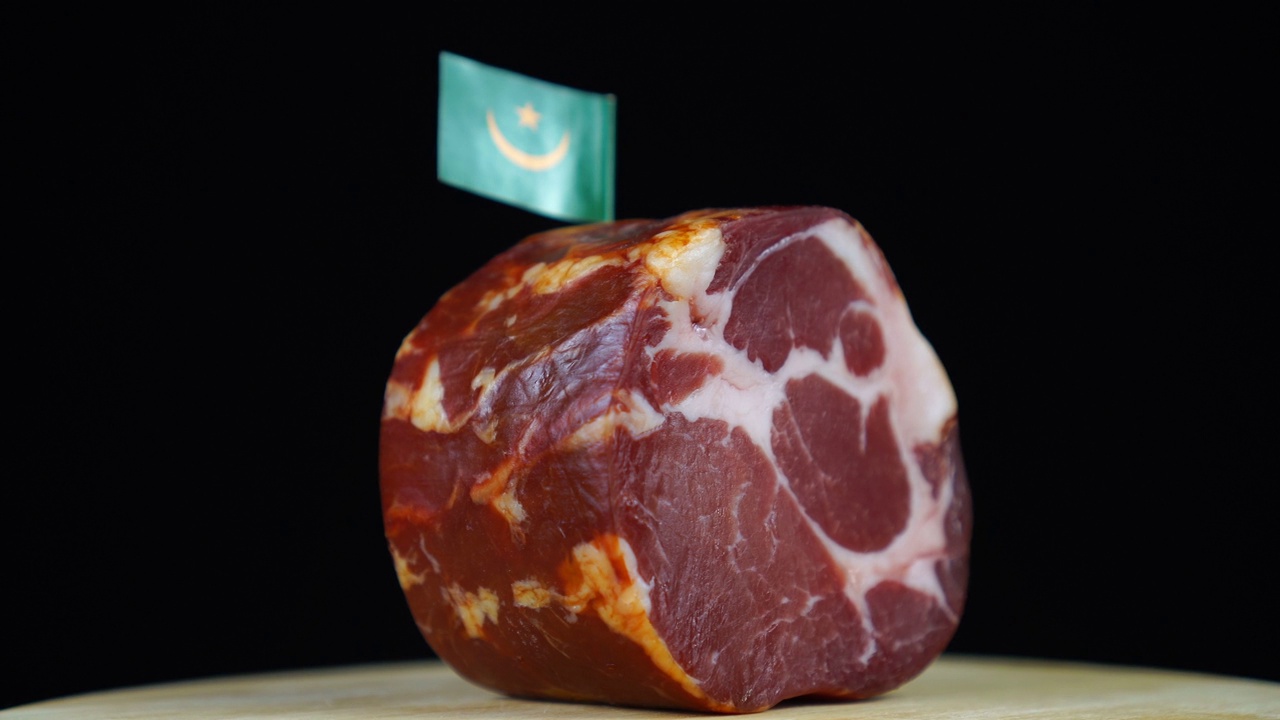 美味的熏里脊肉配上毛里塔尼亚的小旗，黑色背景上的一块肉旋转着。视频下载