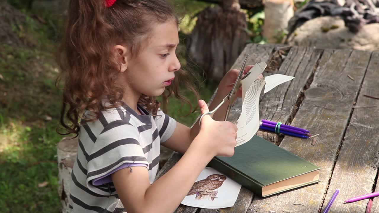 一个小女孩在后院剪纸做贴花的侧视图视频下载