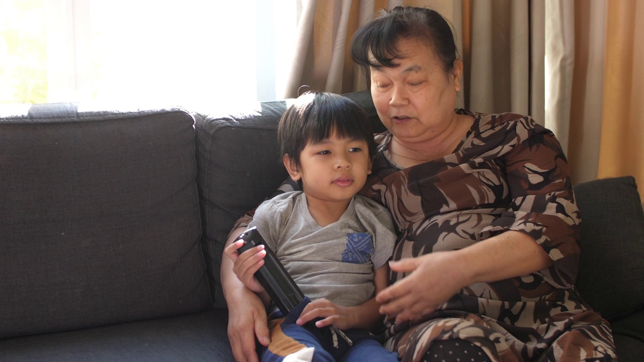 快乐的小男孩和奶奶在家里看电视视频素材