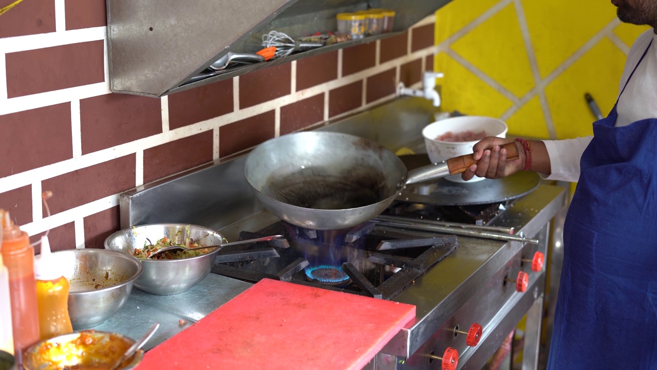 印度厨师在烹饪锅里预热油。视频下载