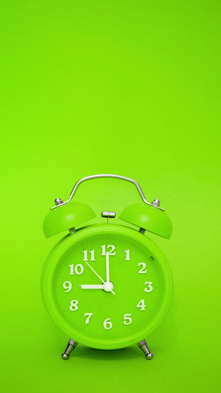 绿色经典闹钟的绿色背景在上午9点响-垂直视频与声音视频下载