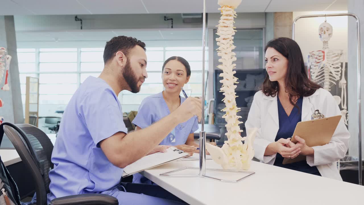 男医学院学生讨论人体脊柱，同时看着一个脊柱模型视频素材