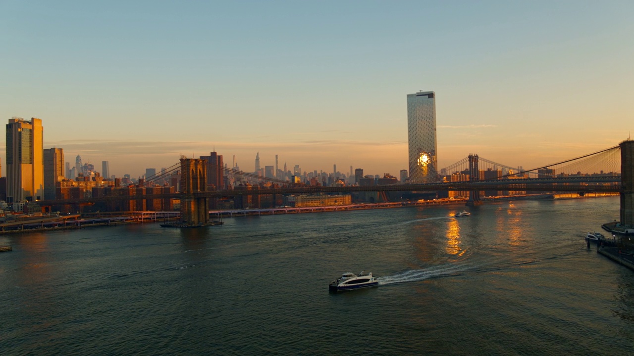 从远处可以看到曼哈顿天际线和布鲁克林大桥，以及沿着东河的曼哈顿大桥。无人机视频与前摇摄像机运动。视频素材