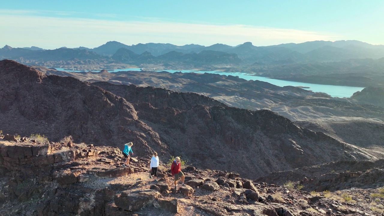 徒步旅行的家庭攀登沙漠地面上的岩石山脊视频素材