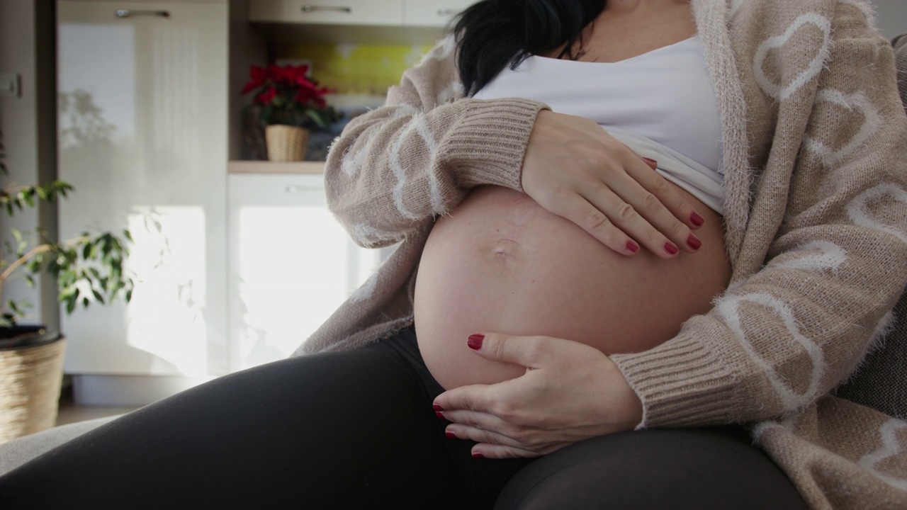 怀孕晚期的年轻女子抚摸着自己的肚子视频素材