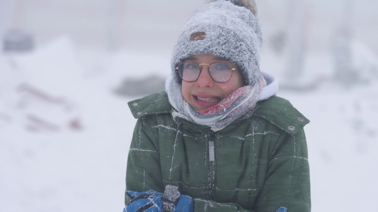一个十几岁的男孩的肖像，在一个冬天的风雪中非常寒冷视频下载