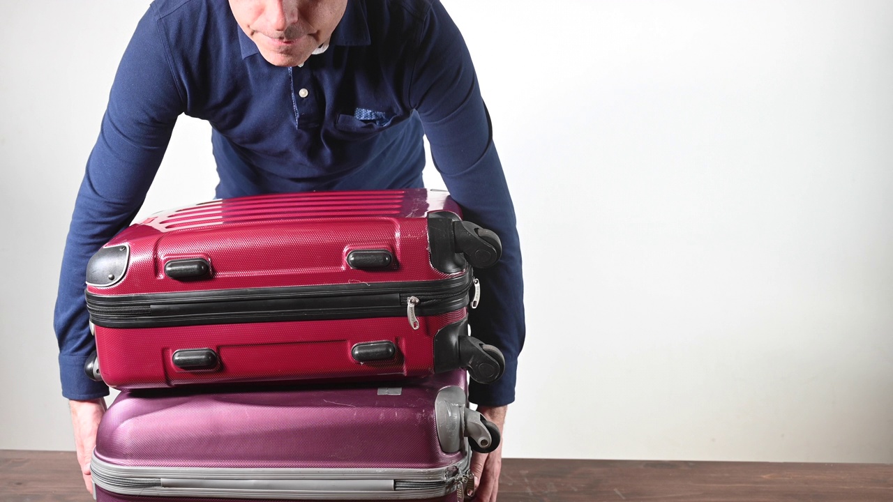 一个男人带着两个沉重的手提箱去旅行。视频下载