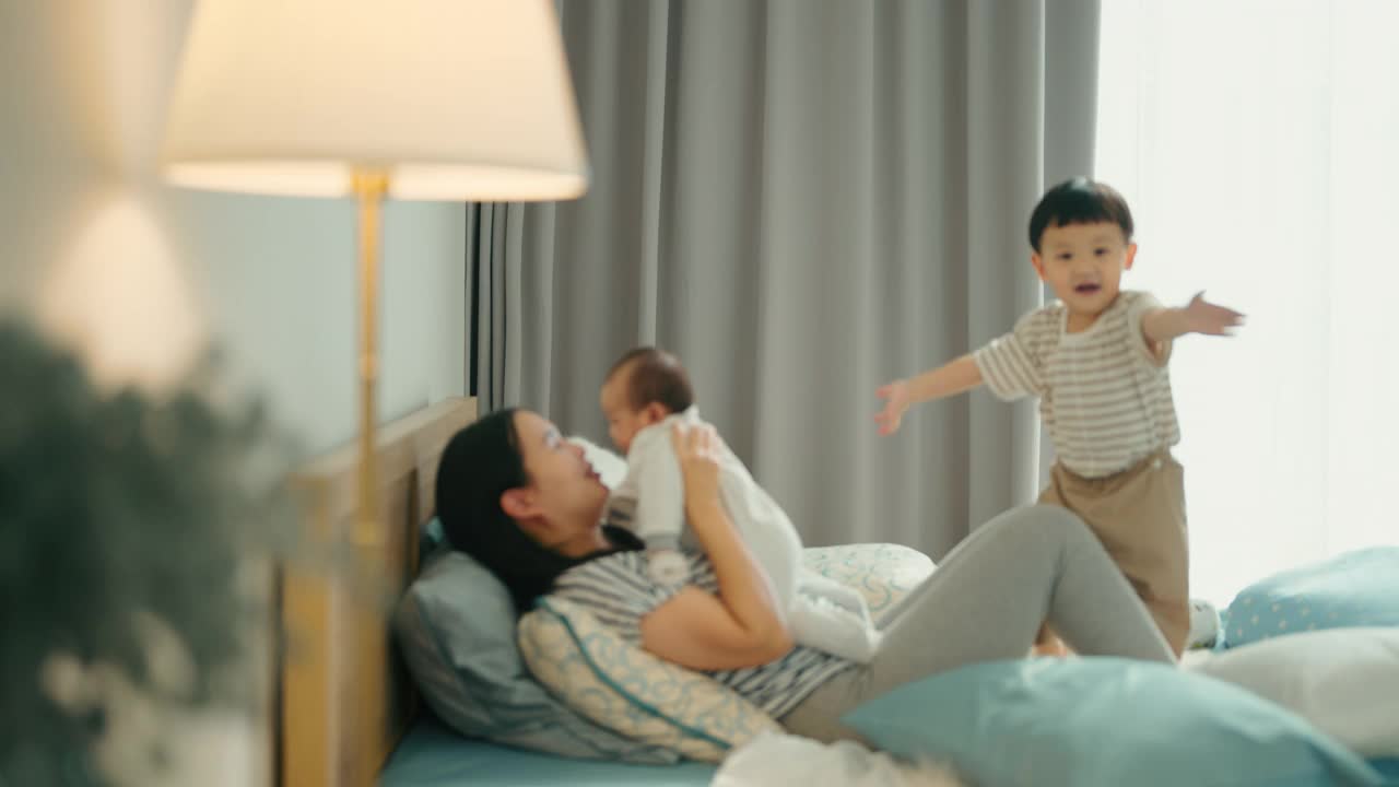 微笑的亚洲母亲玩抱着她可爱的新生男婴视频下载