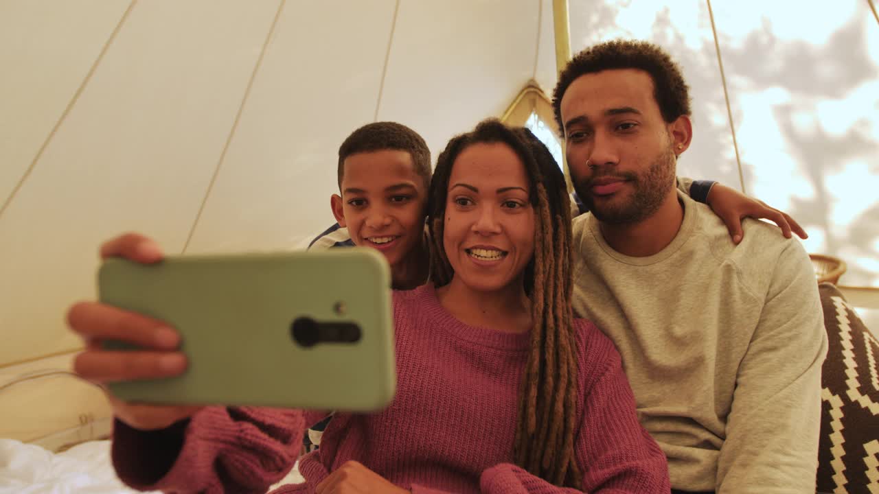 好玩的，愚蠢的家庭做鬼脸，在帐篷里用手机拍照视频下载