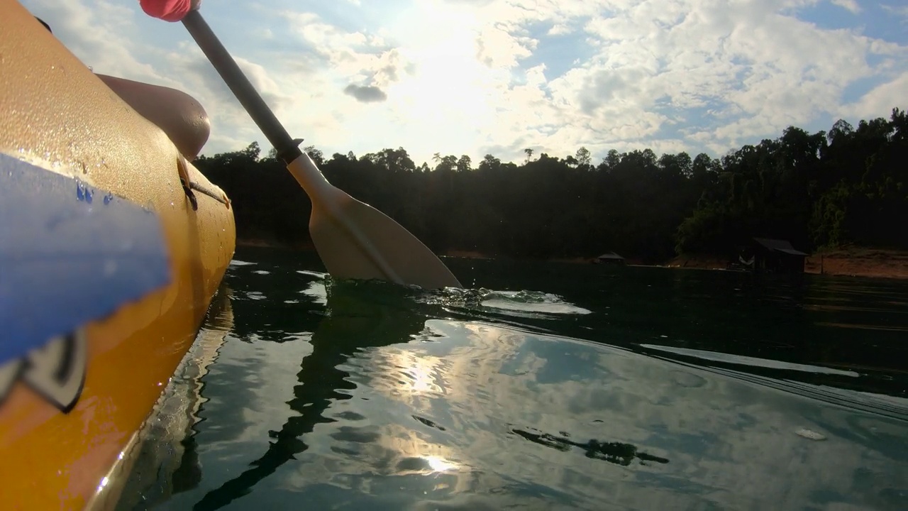 亚洲妇女皮划艇在早晨与阳光热带大湖。放松的运动视频下载