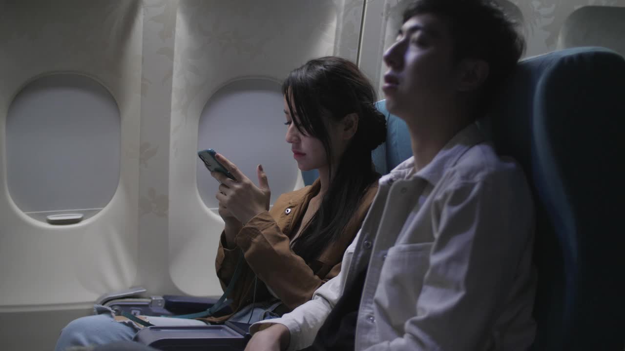 女乘客在夜间飞行时使用智能手机视频下载
