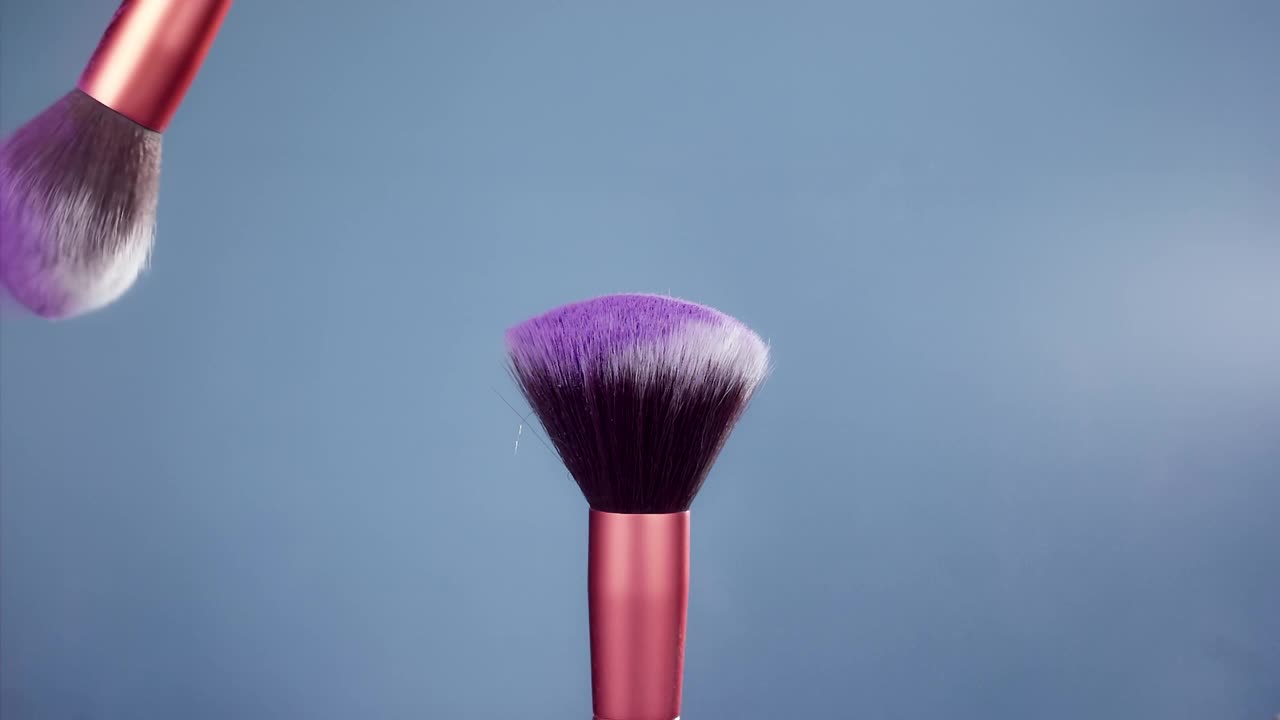 化妆刷与紫色粉末爆炸在蓝色背景超级慢动作视频素材