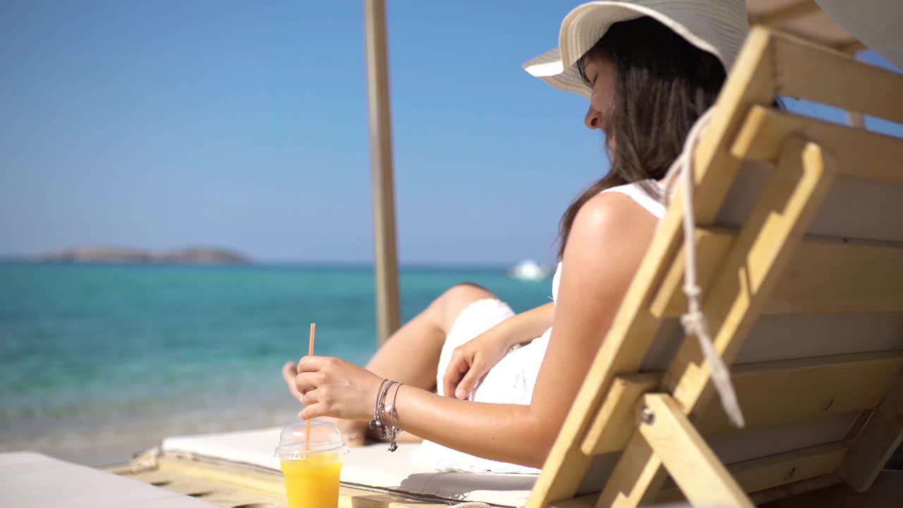 年轻女子在海滩上享受橙汁视频下载