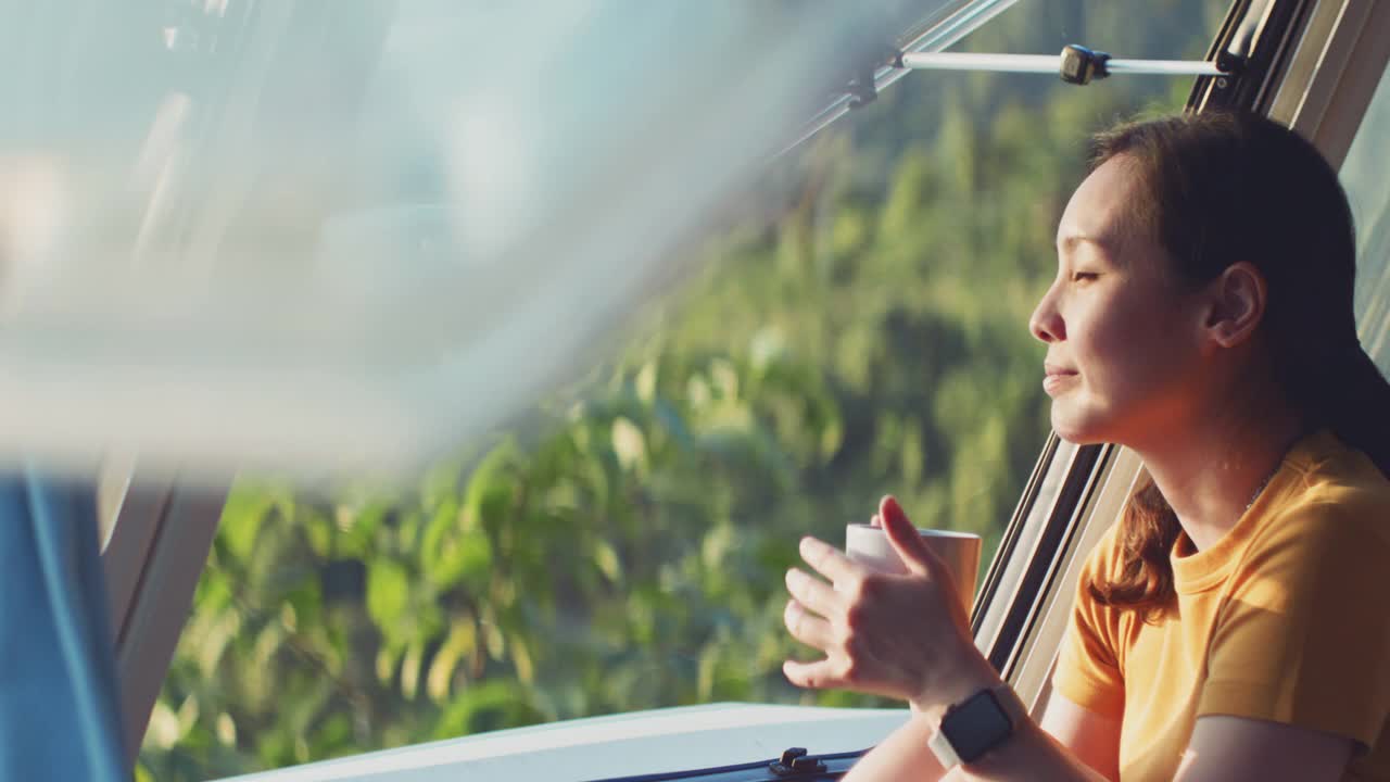 亚洲妇女感觉放松在露营车喝咖啡的早晨与幸福和微笑的假期视频下载