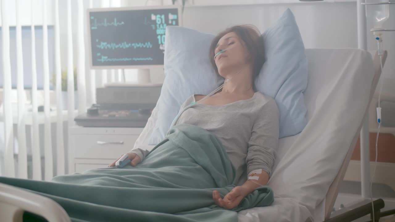 带着鼻氧管和滴管的年轻病人躺在病床上视频下载