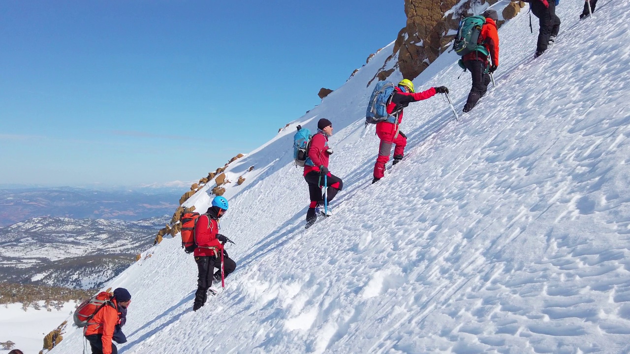 高山高山登山队冬季在高海拔山峰上排成一行行走视频下载