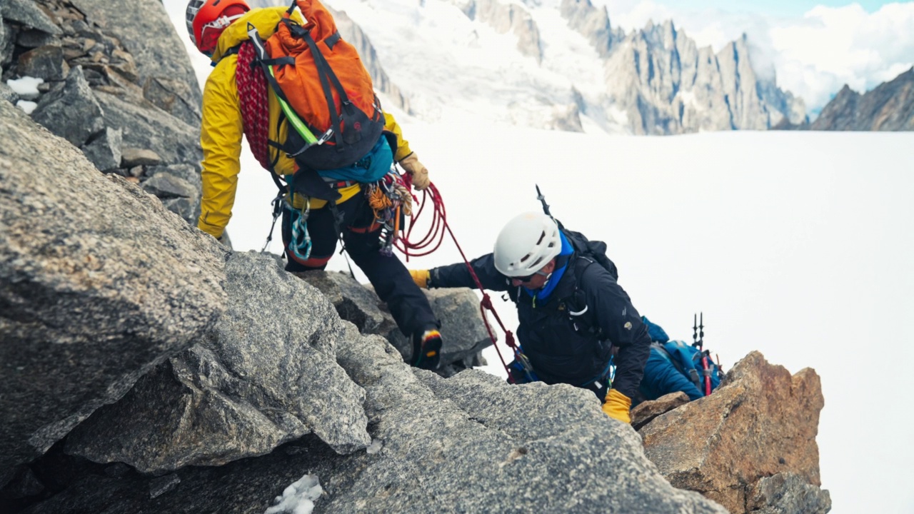 欧洲阿尔卑斯山脉上的山峰被冰山覆盖。攀岩者在陡峭的岩壁上行走视频下载