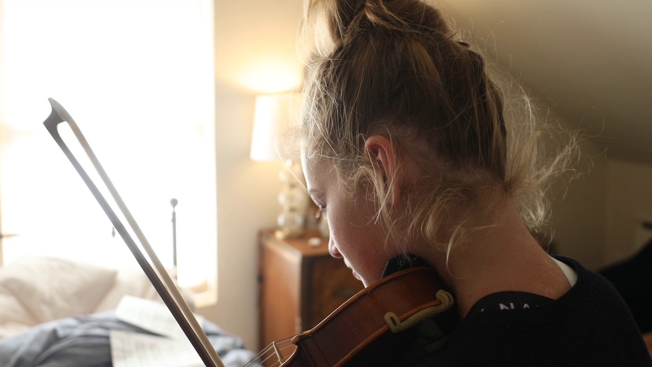 十几岁的女孩在卧室里拉小提琴视频素材