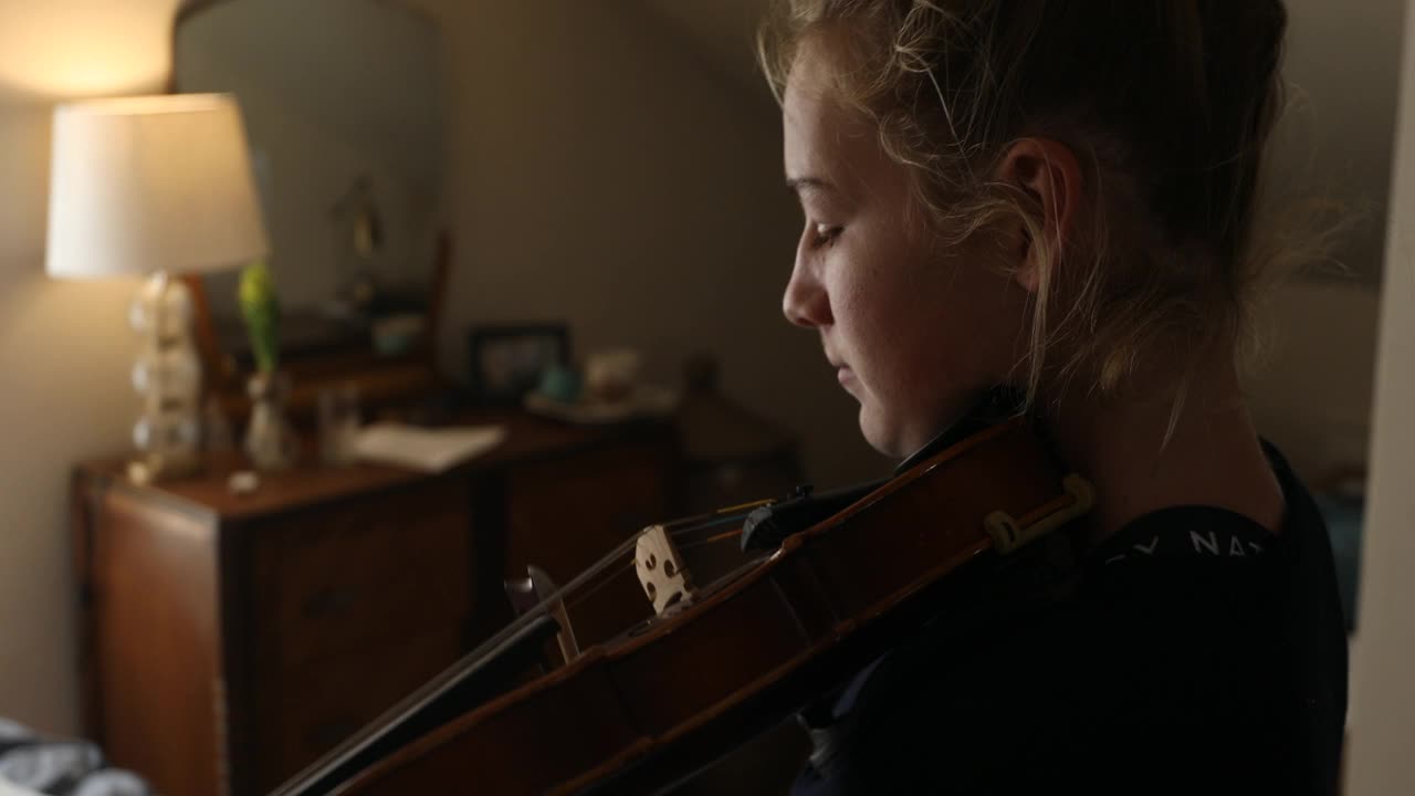 十几岁的女孩在卧室里拉小提琴视频素材