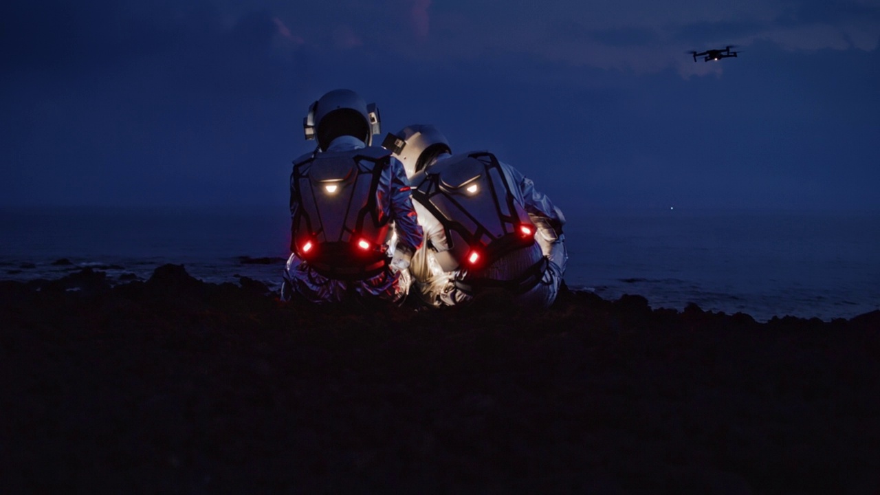 宇航员穿着未来主义服装，带着发光的平板电脑在新星球上寻找路线。坐在荒凉的海岸上视频下载