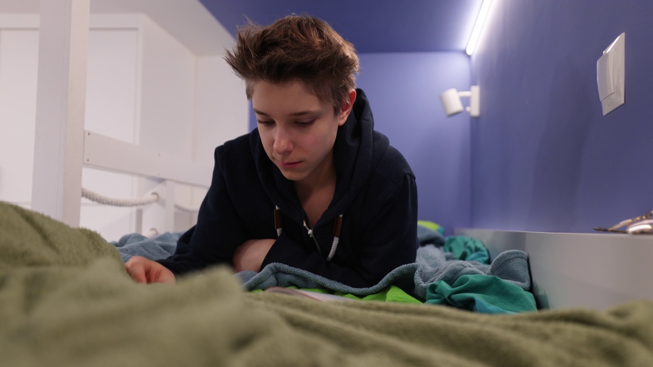 一个十几岁的男孩躺在床上准备上学视频素材