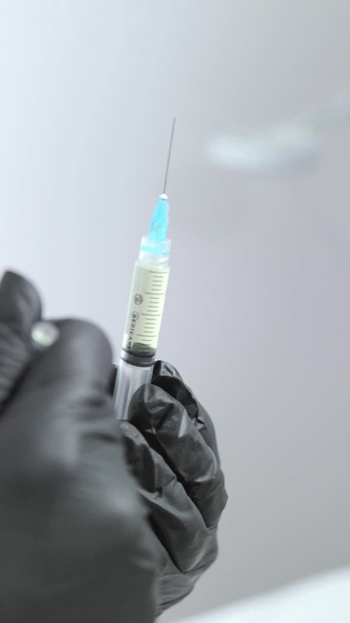 医务工作者的手握着一个装有药物的注射器。视频下载